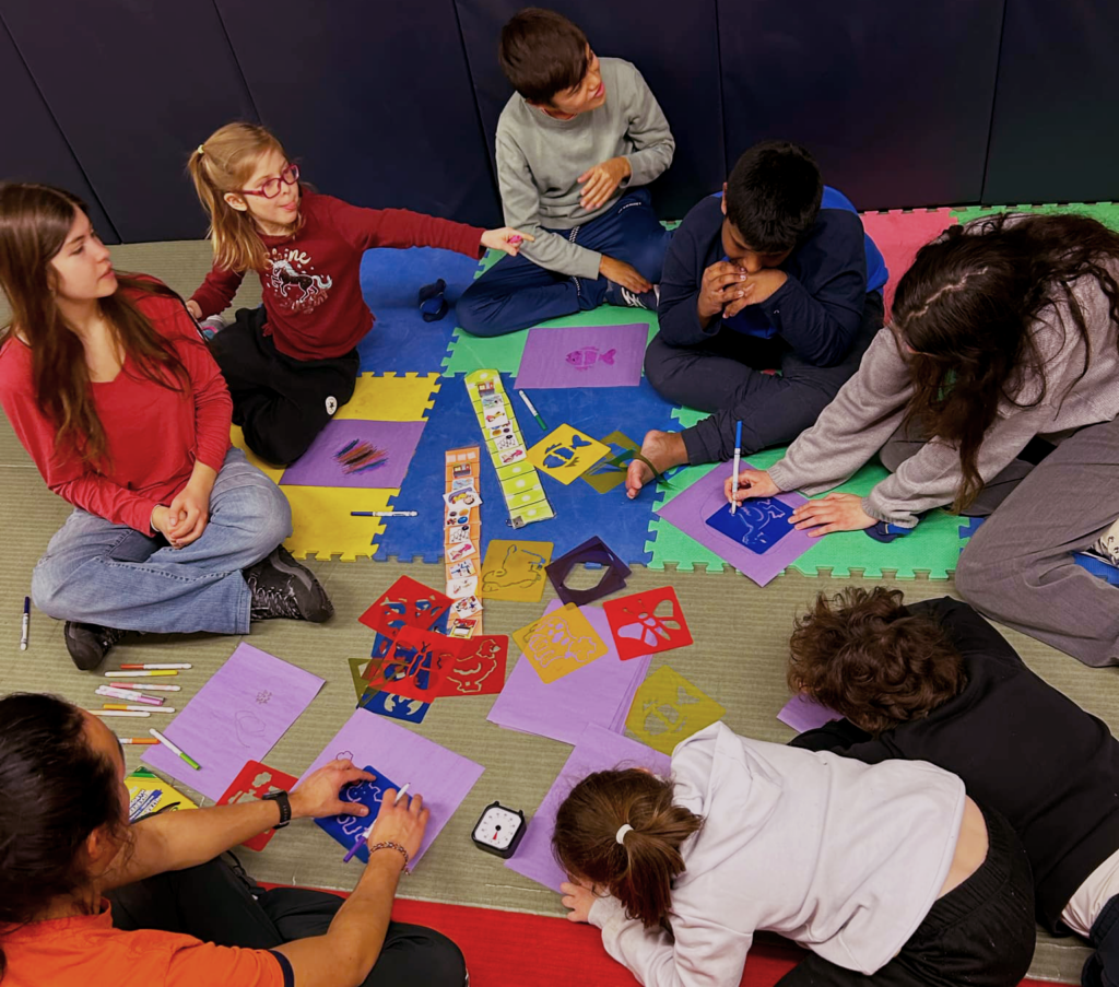 Des enfants assis en cercle sur des tapis colorés, faisant du bricolage ensemble.