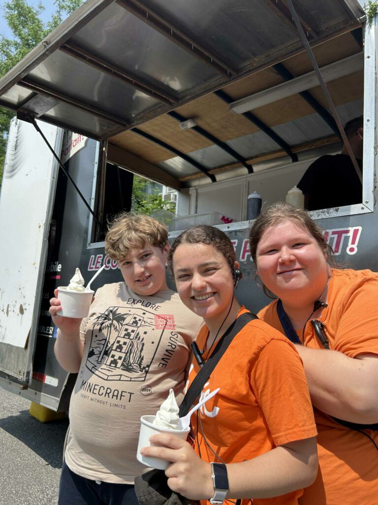 Jeune et deux accompagnatrices souriants avec de la crème glacée à la main.
