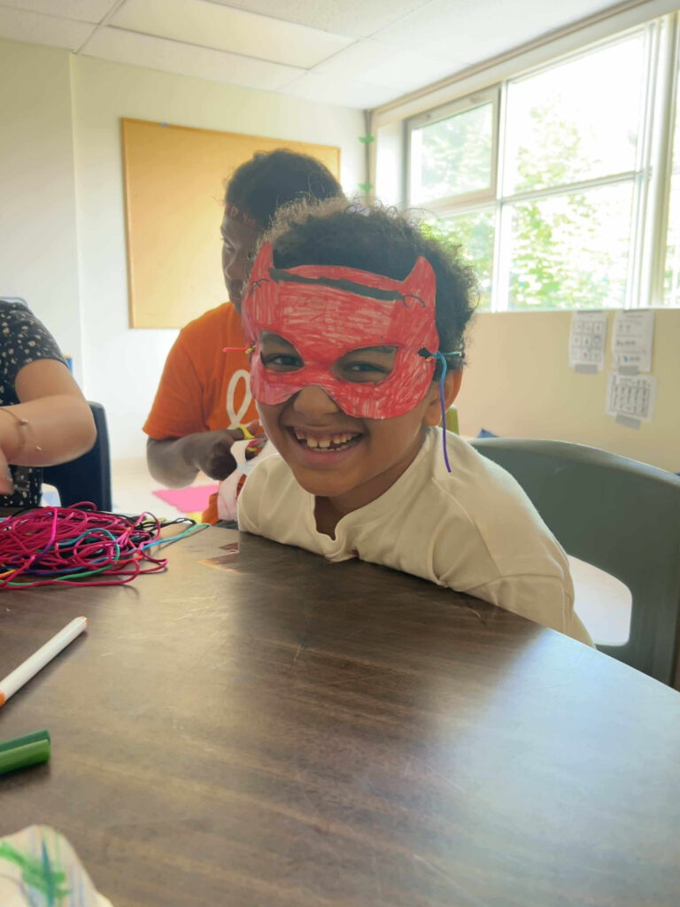 Jeune avec un masque de super-héro, fier d'avoir fait le bricolage.