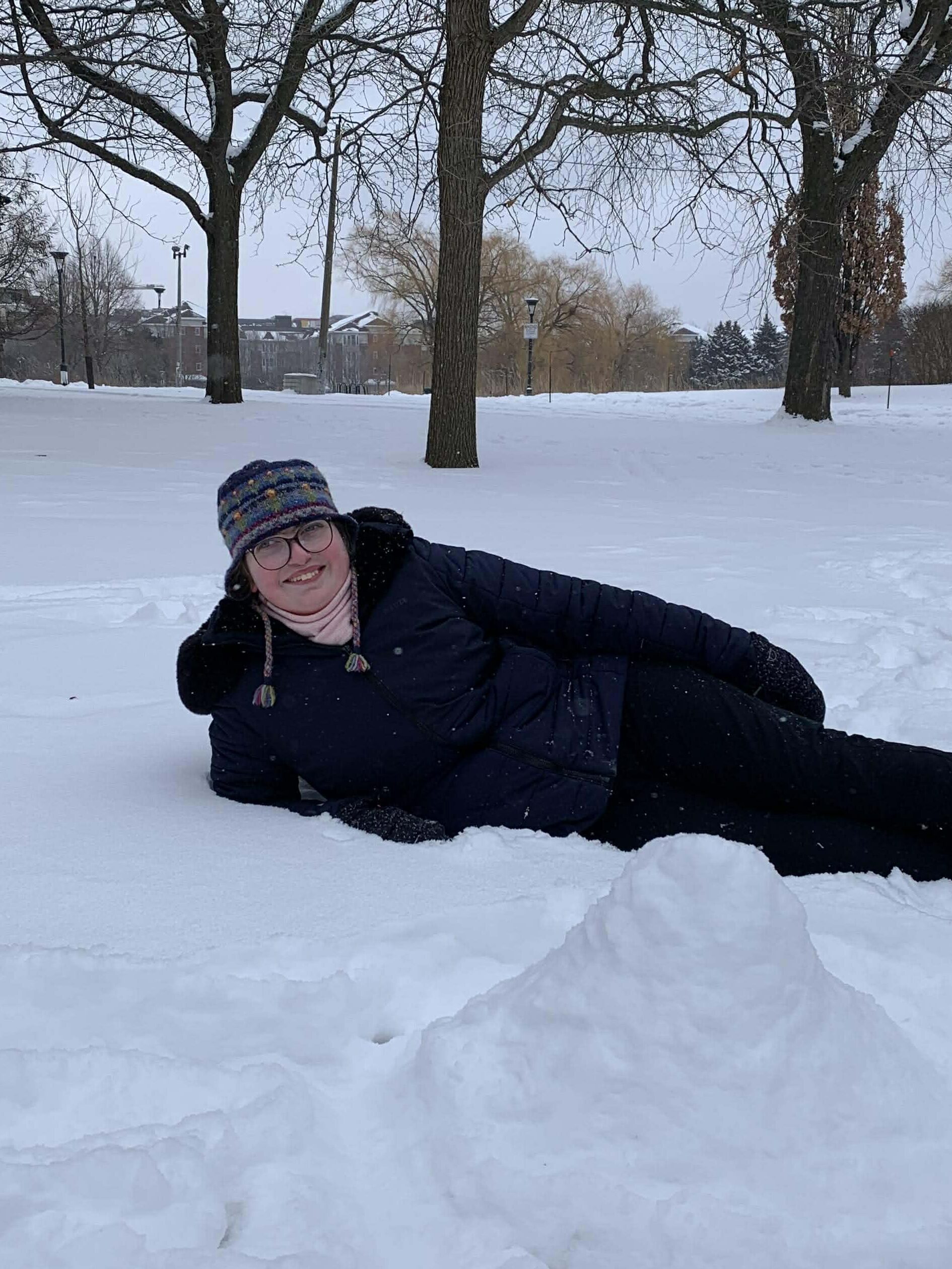 Adolescente souriante allongée sur le côté dans la neige.