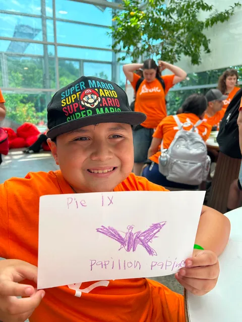 Jeune souriant avec un dessin de papillon à l'insectarium.