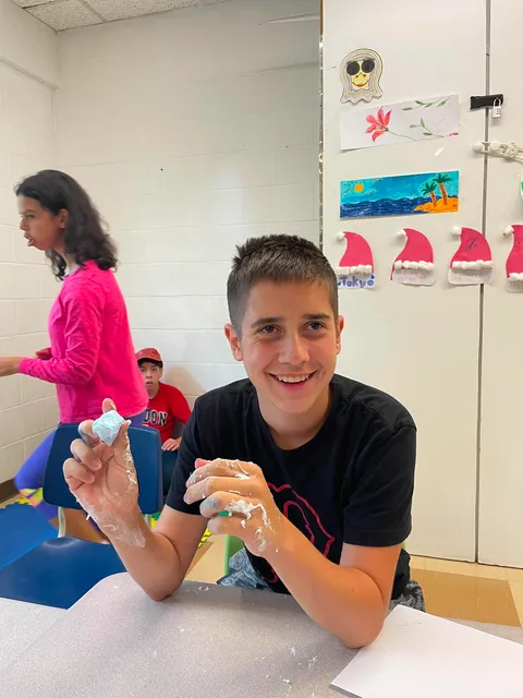 Jeune adolescent en train de manipuler de la slim durant une activité scientifique au camp de jour.