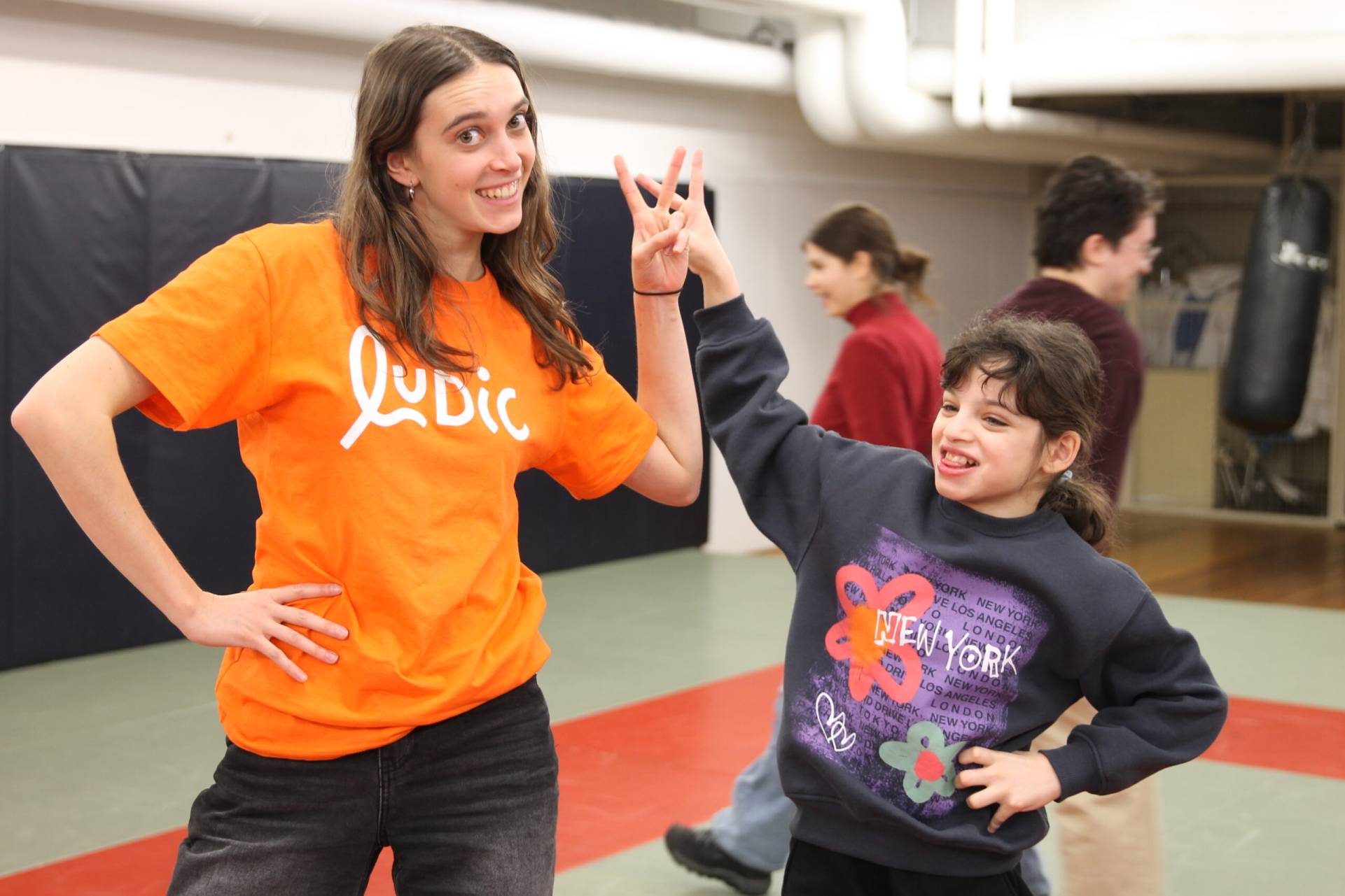 Accompagnatrice et jeune posant avec un sourire et un signe de paix.