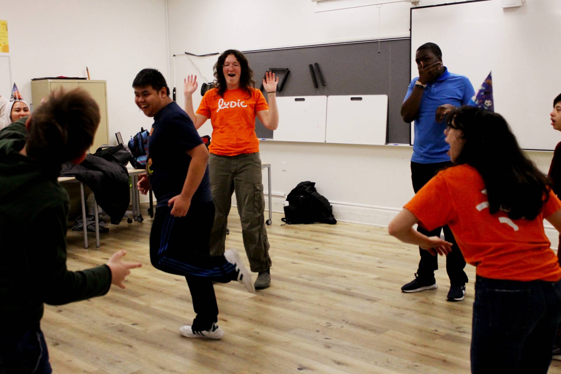 Groupe de jeunes qui danse devant une animation sur la télévision.